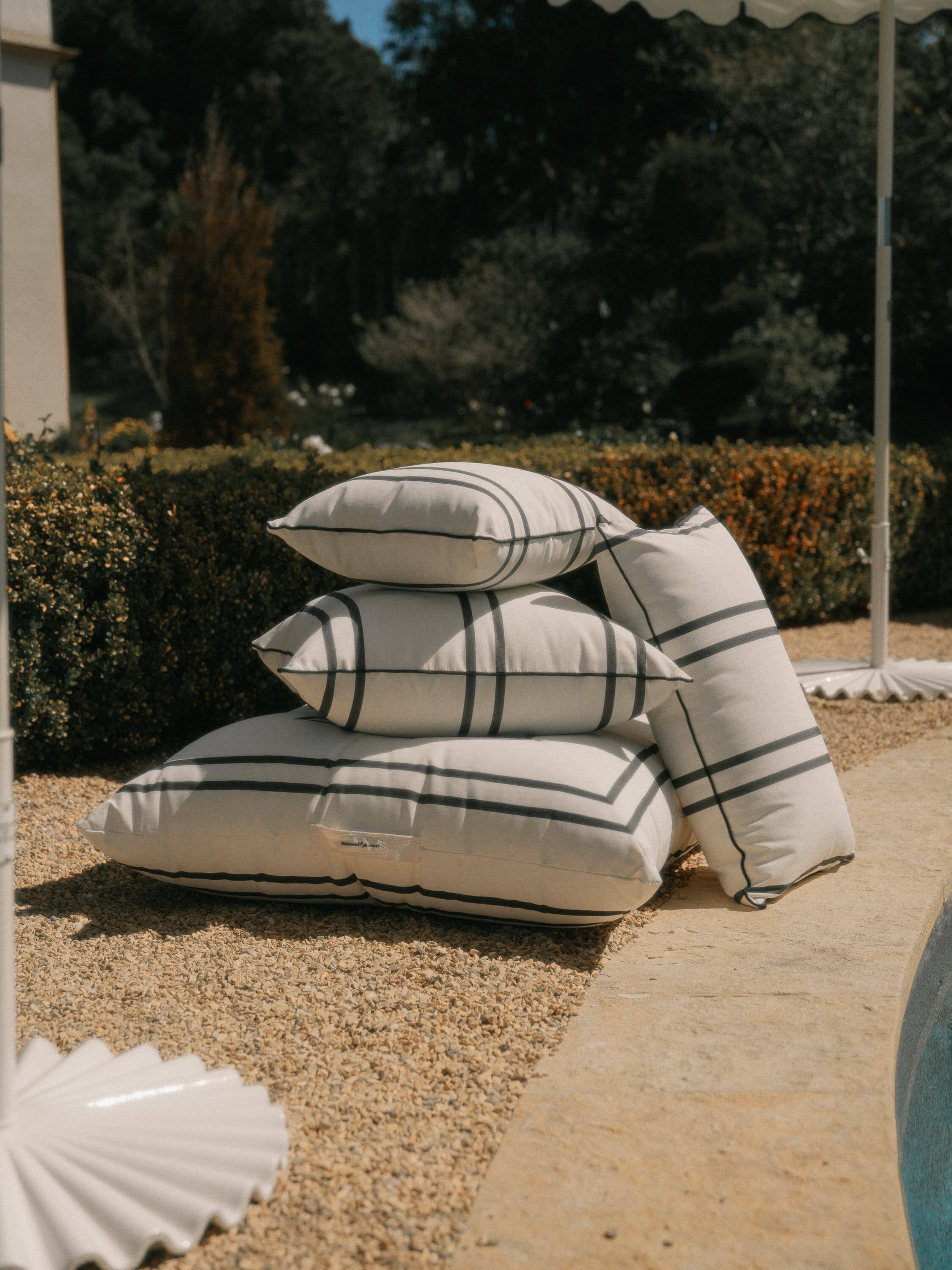 stack of malibu black stripe pillows next to a pool