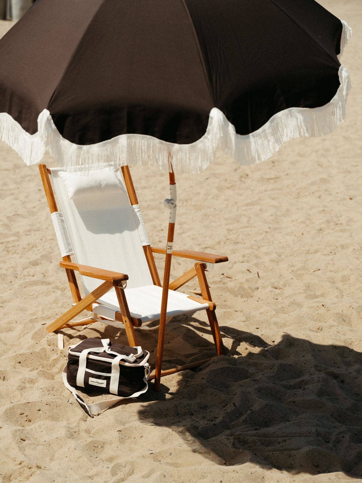 Vintage black holiday cooler, umbrella and white chair on the beach