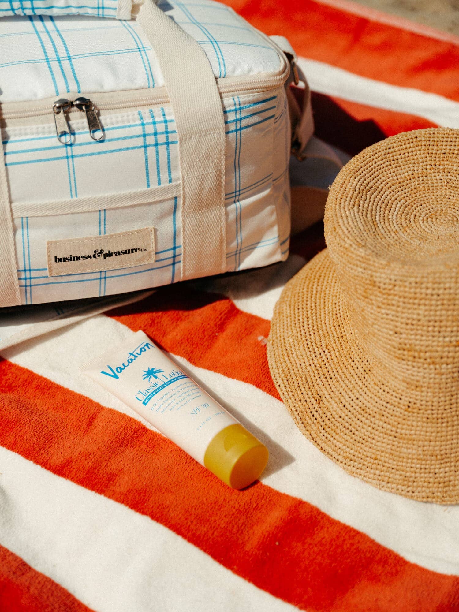 Blue plaid holiday cooler and le sirenuse beach towel with beach hat and sunscreen