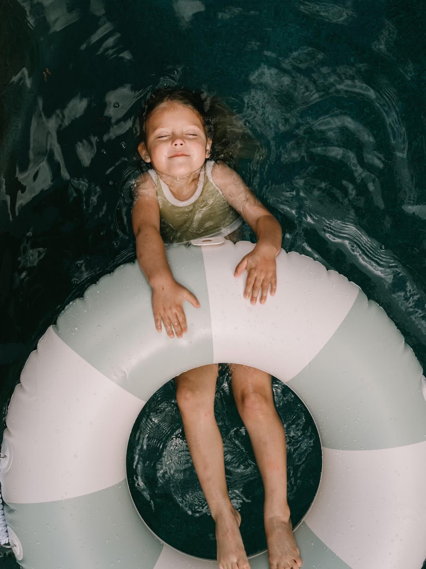 Little girl floating on a pool float in the pool