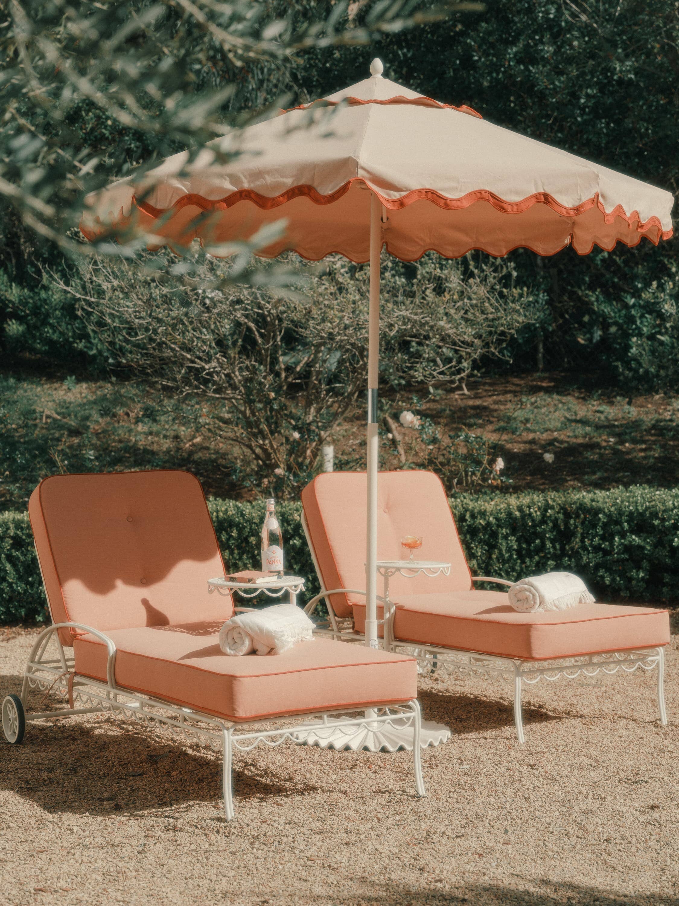 Riviera pink market umbrella and pink sun loungers on a patio