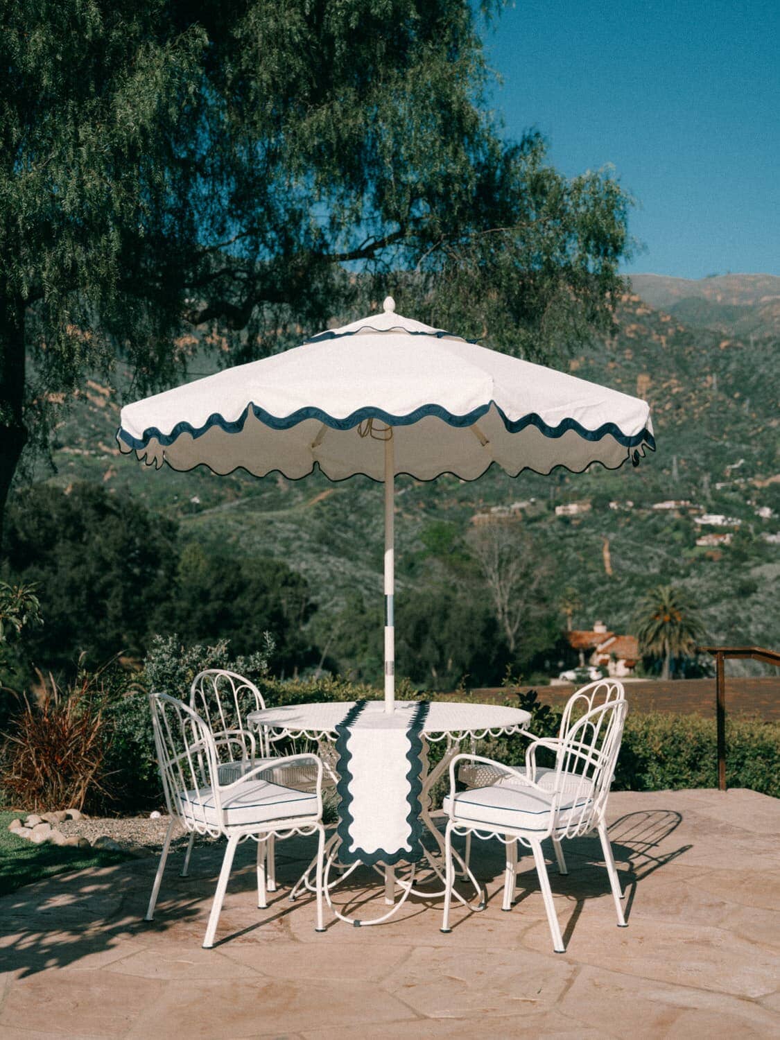 White riviera market umbrella with an alfresco dining table and chairs on a garden patio