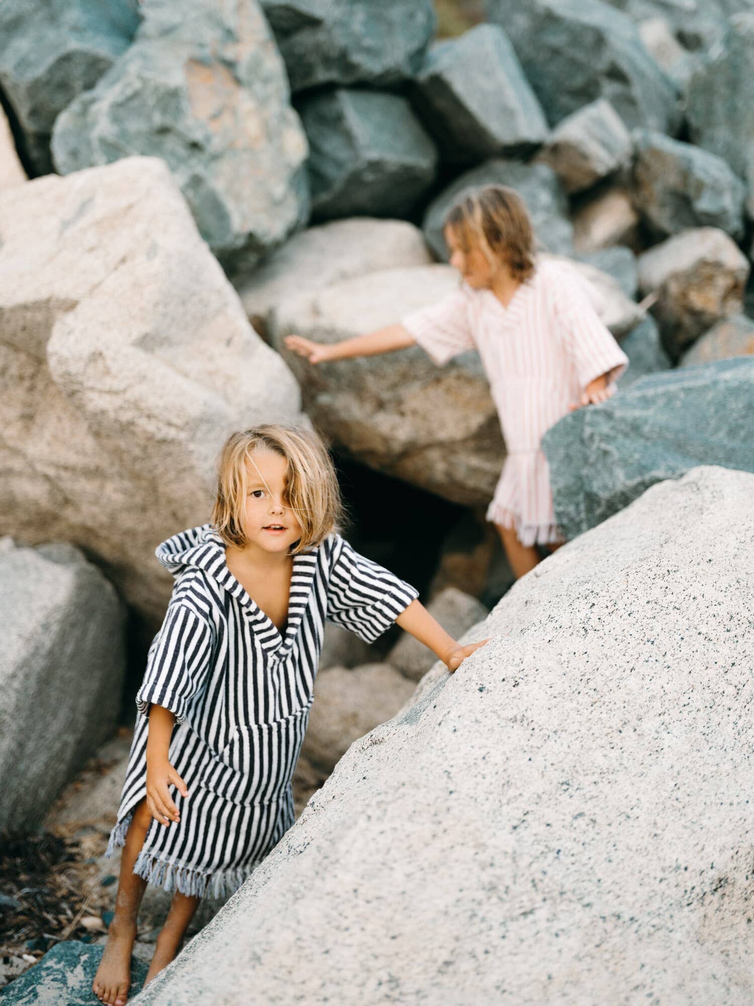 Children in ponchos playing on rocks
