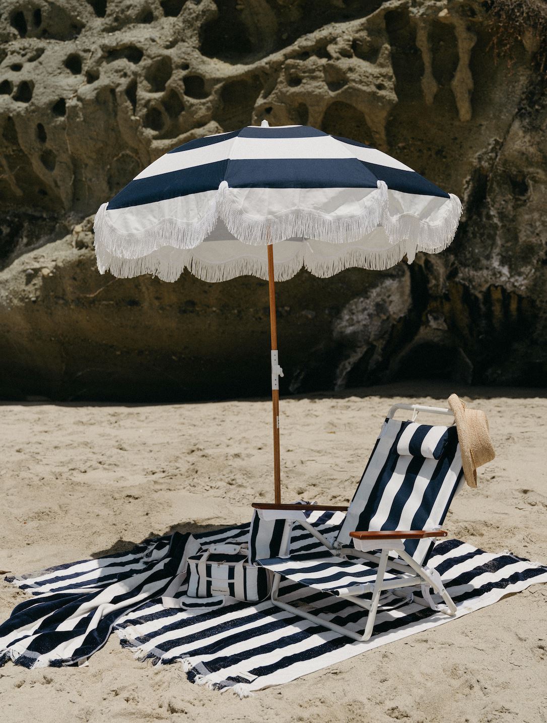 beach scene with navy umbrella, chair, blanket and cooler bag