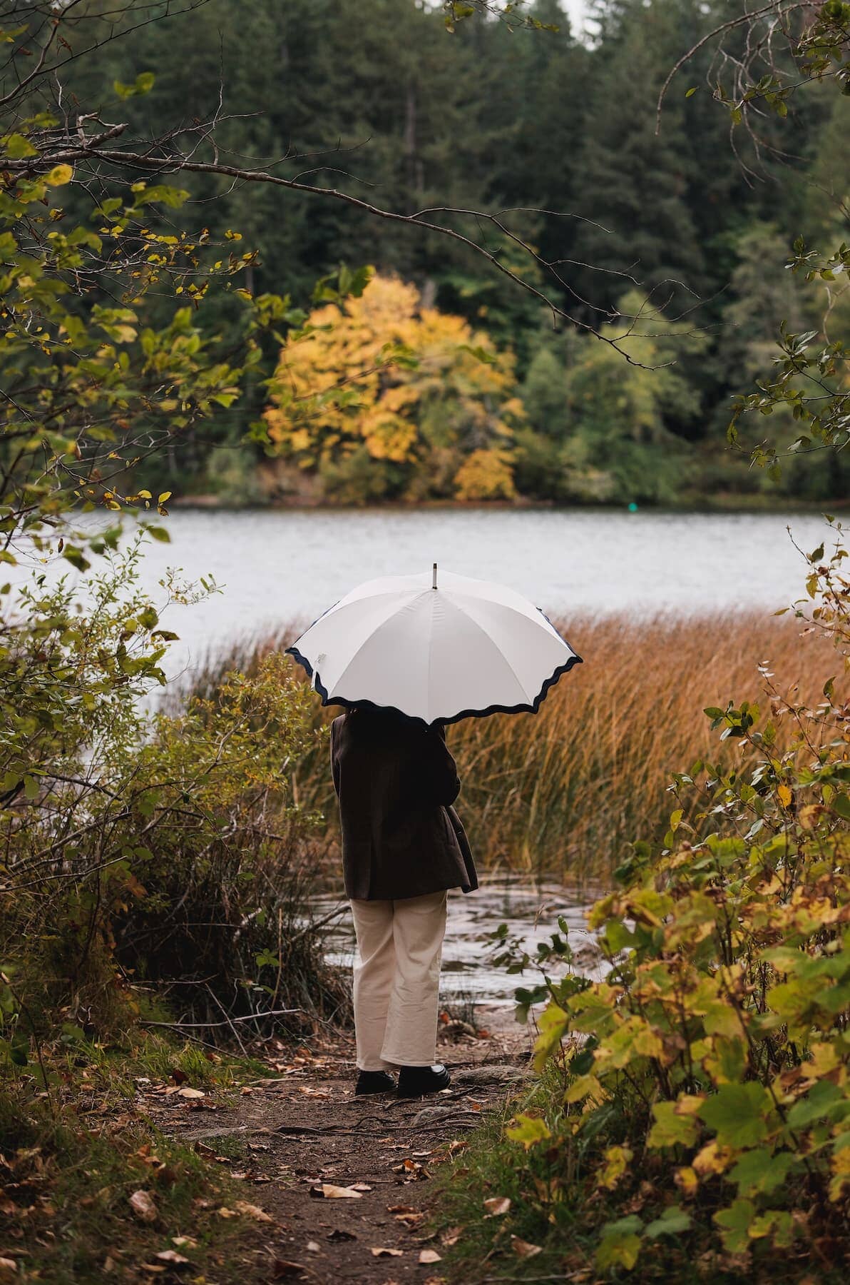 Rivie white rain umbrella in the woods by a lake