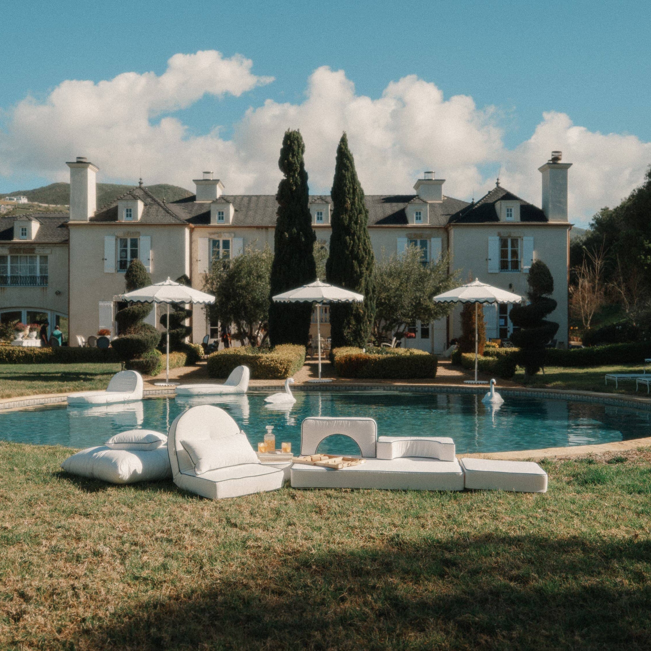 white reclining lounger by the pool with white pillows and cushions