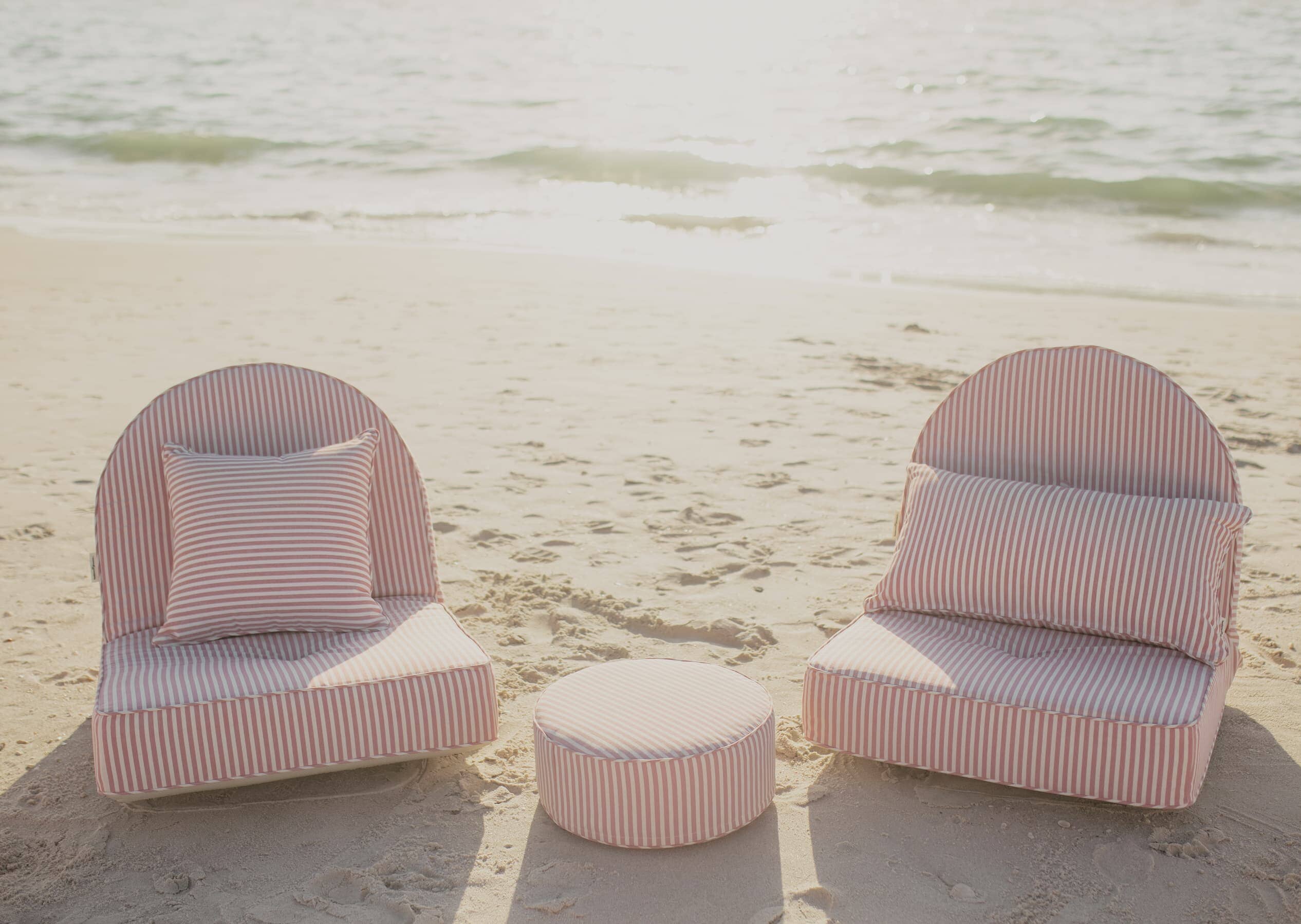 pink throw pillows on the beach with reclining pillow loungers