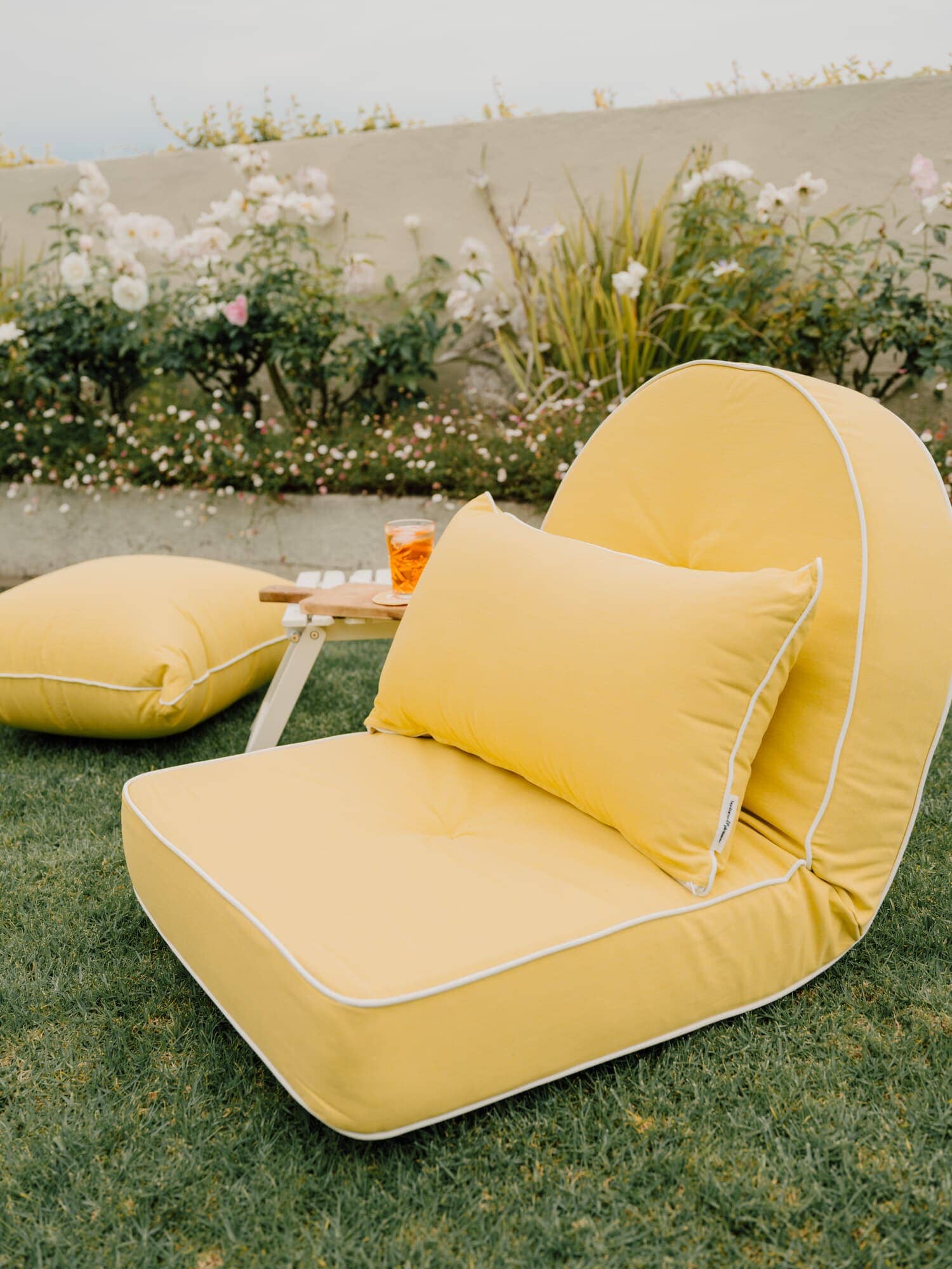 Riviera mimosa throe pillow on a reclining lounger in a garden setting