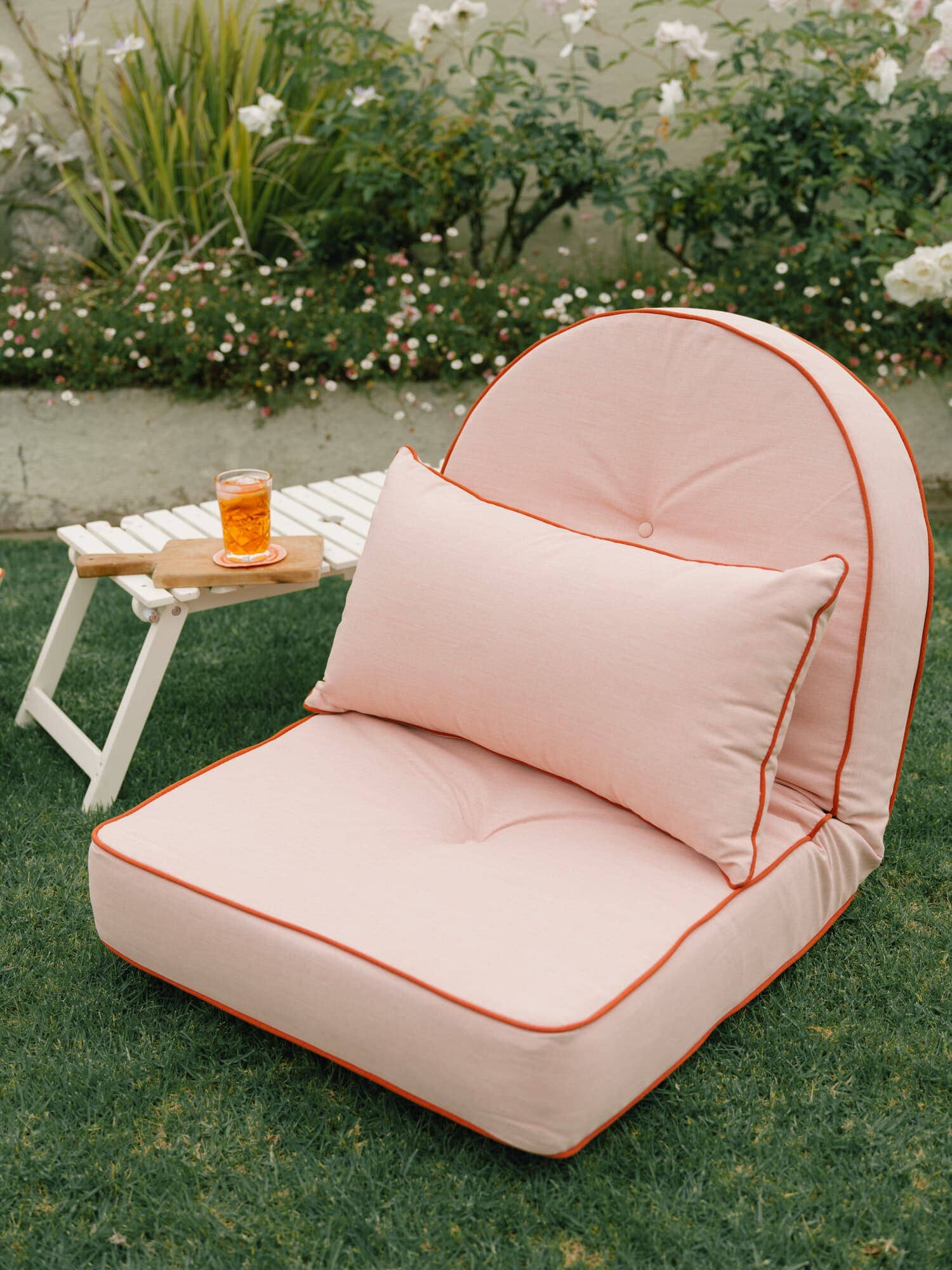 Riviera pink throw pillow on reclining pillow lounger in a garden setting