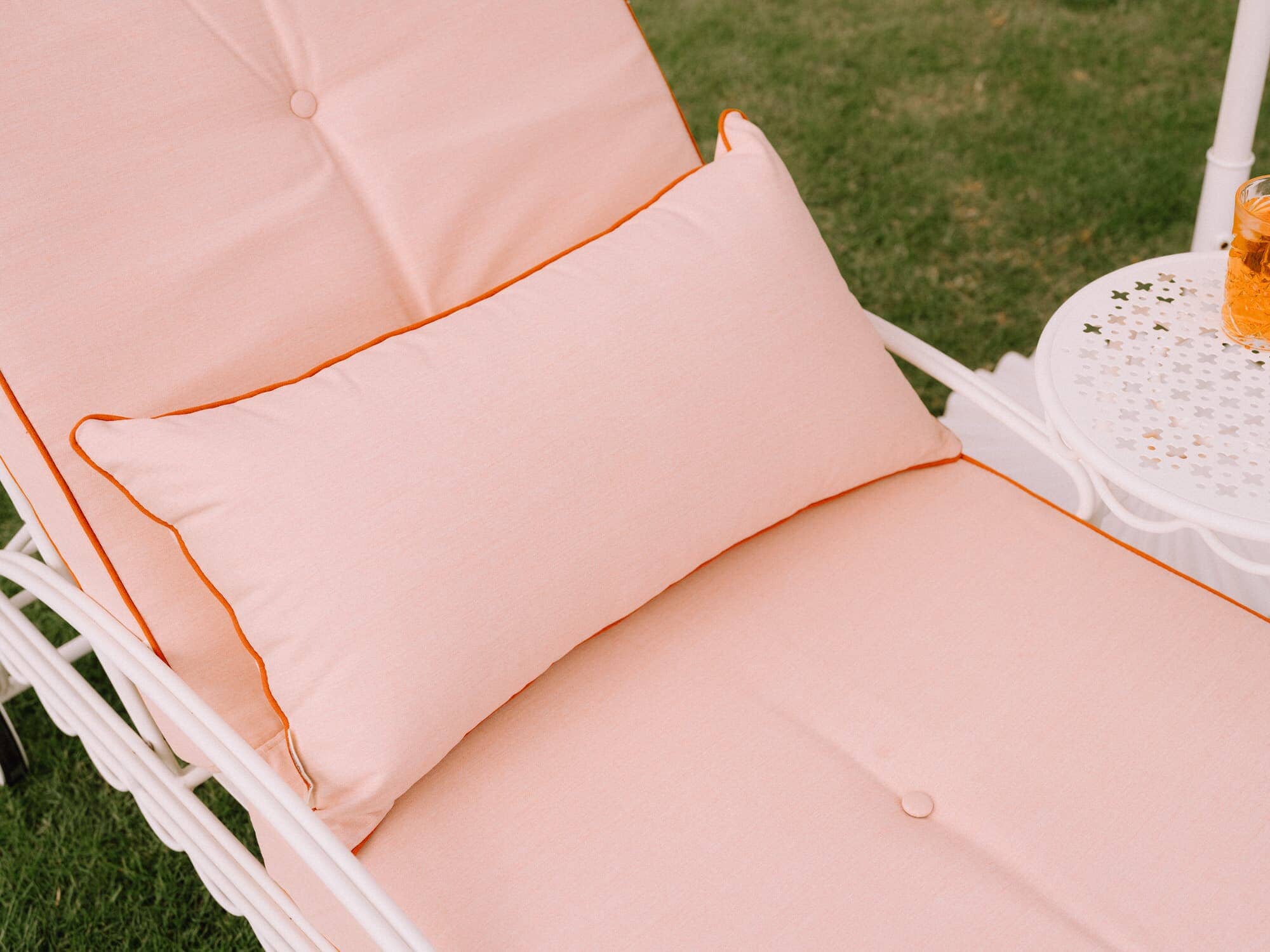 Riviera pink throw pillow on reclining sun lounger in a garden setting