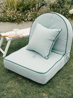 Small throw pillow on reclining lounger in garden setting