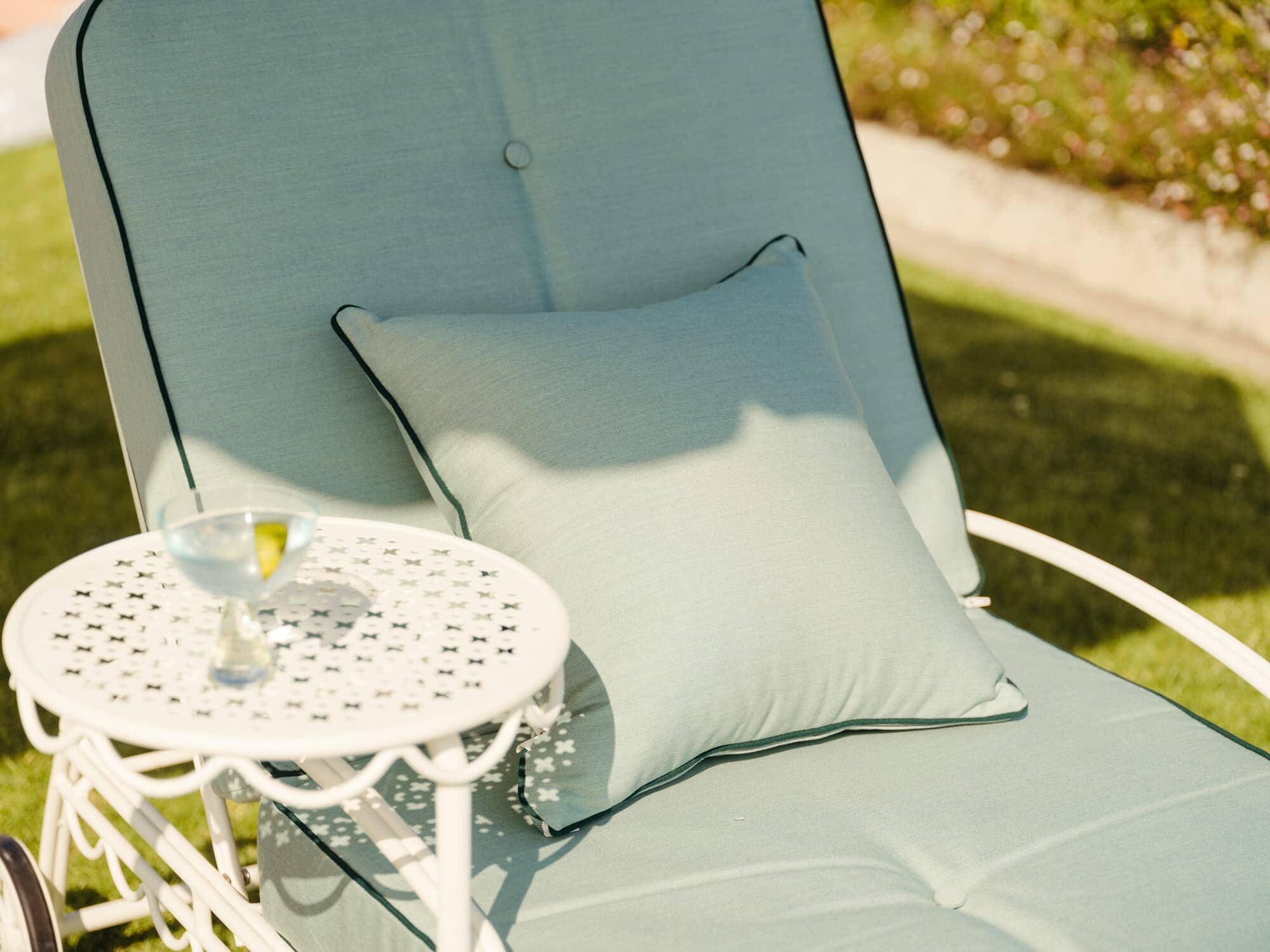 Small throw pillow on sun lounger in garden setting