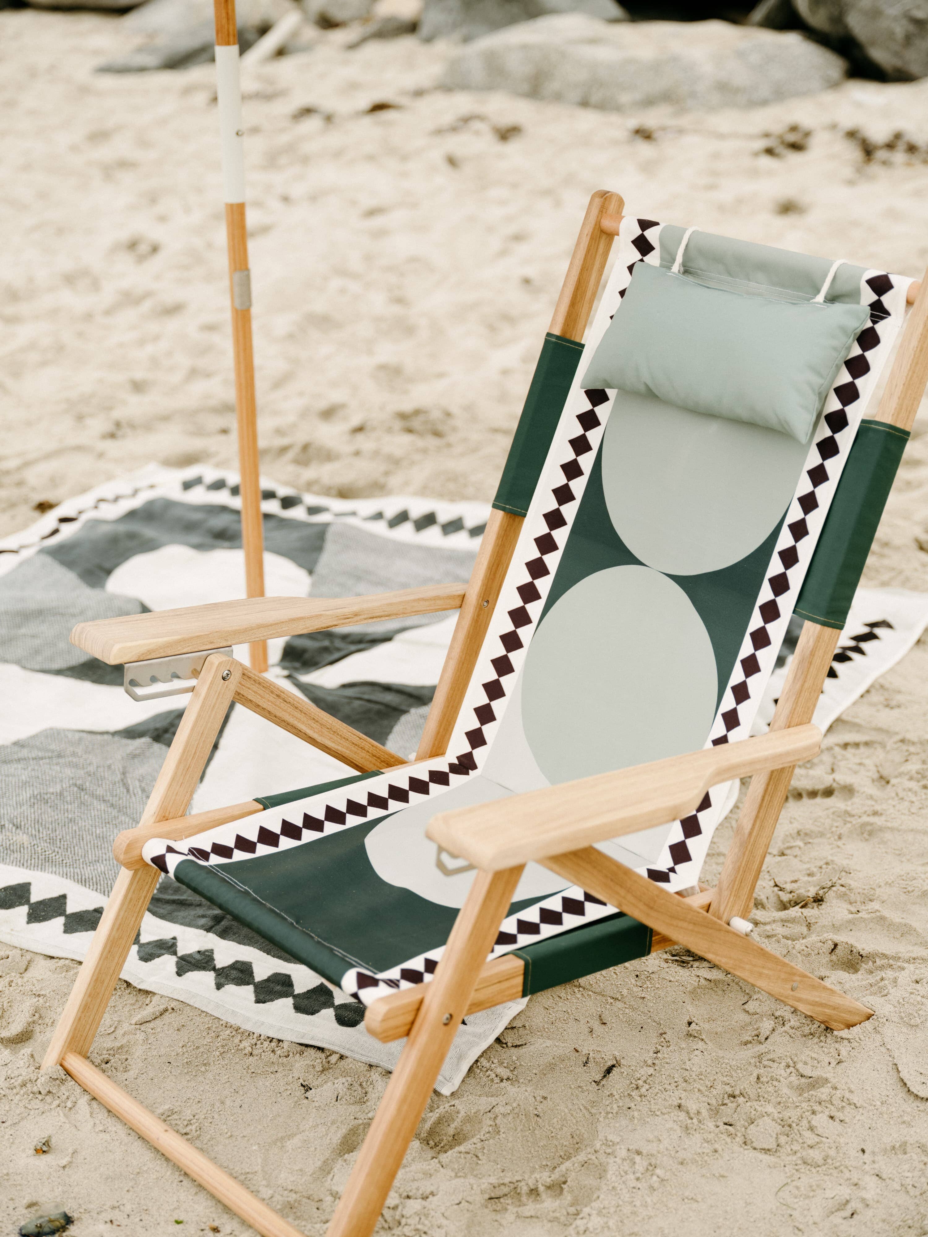 Beach set up with diamond green umbrella, chair and blanket. 