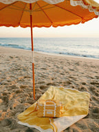 Beach setting with riviera mimosa umbrella, towel & cooler