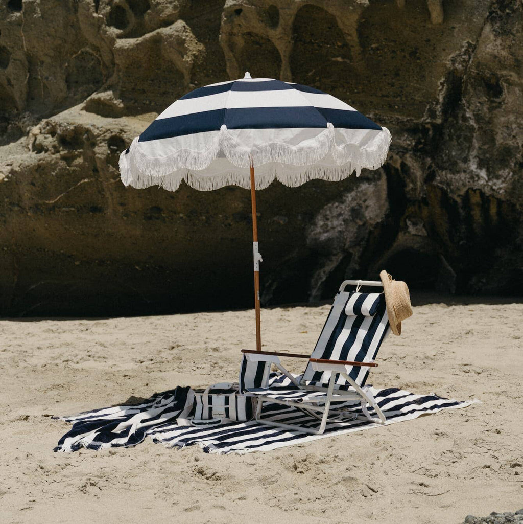 navy holiday beach umbrella on the beach with beach chair and towel