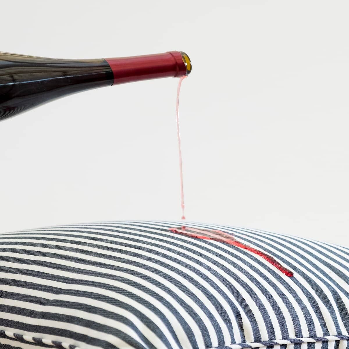 red wine being poured on throw pillow