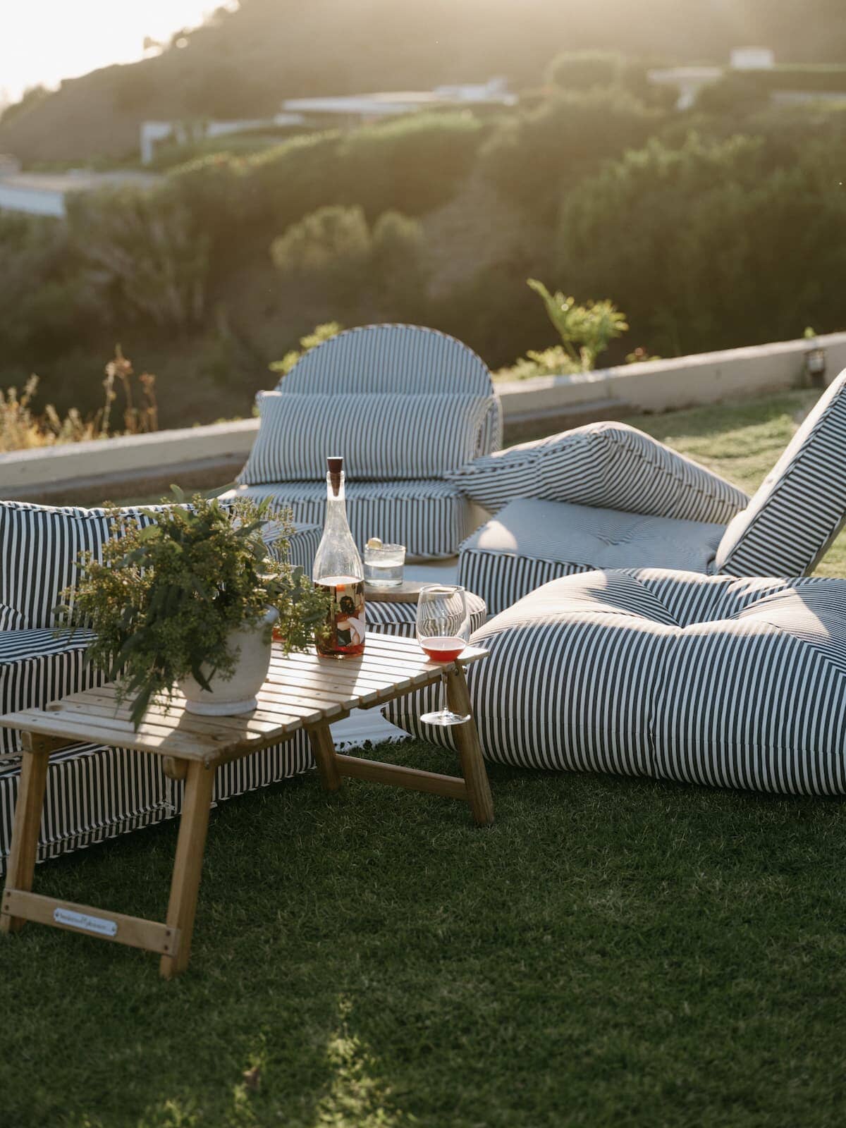 Outdoor picnic setting with a folding table and scattered floor cushions on the grass