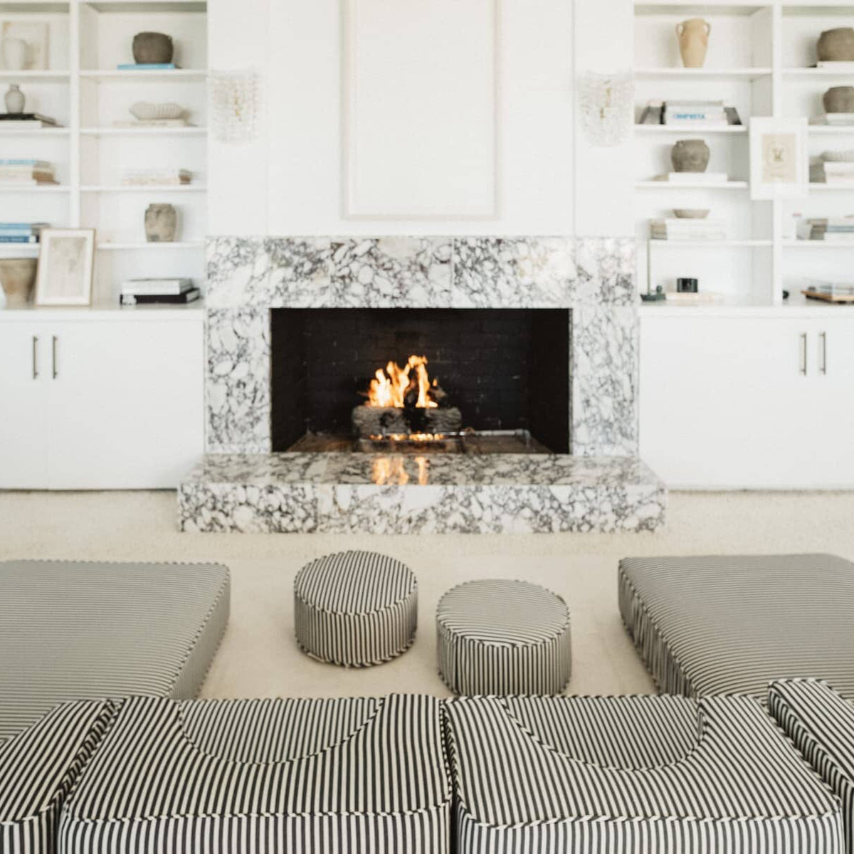 The navy stripe modular pillow stack arranged in front of a living room fire place