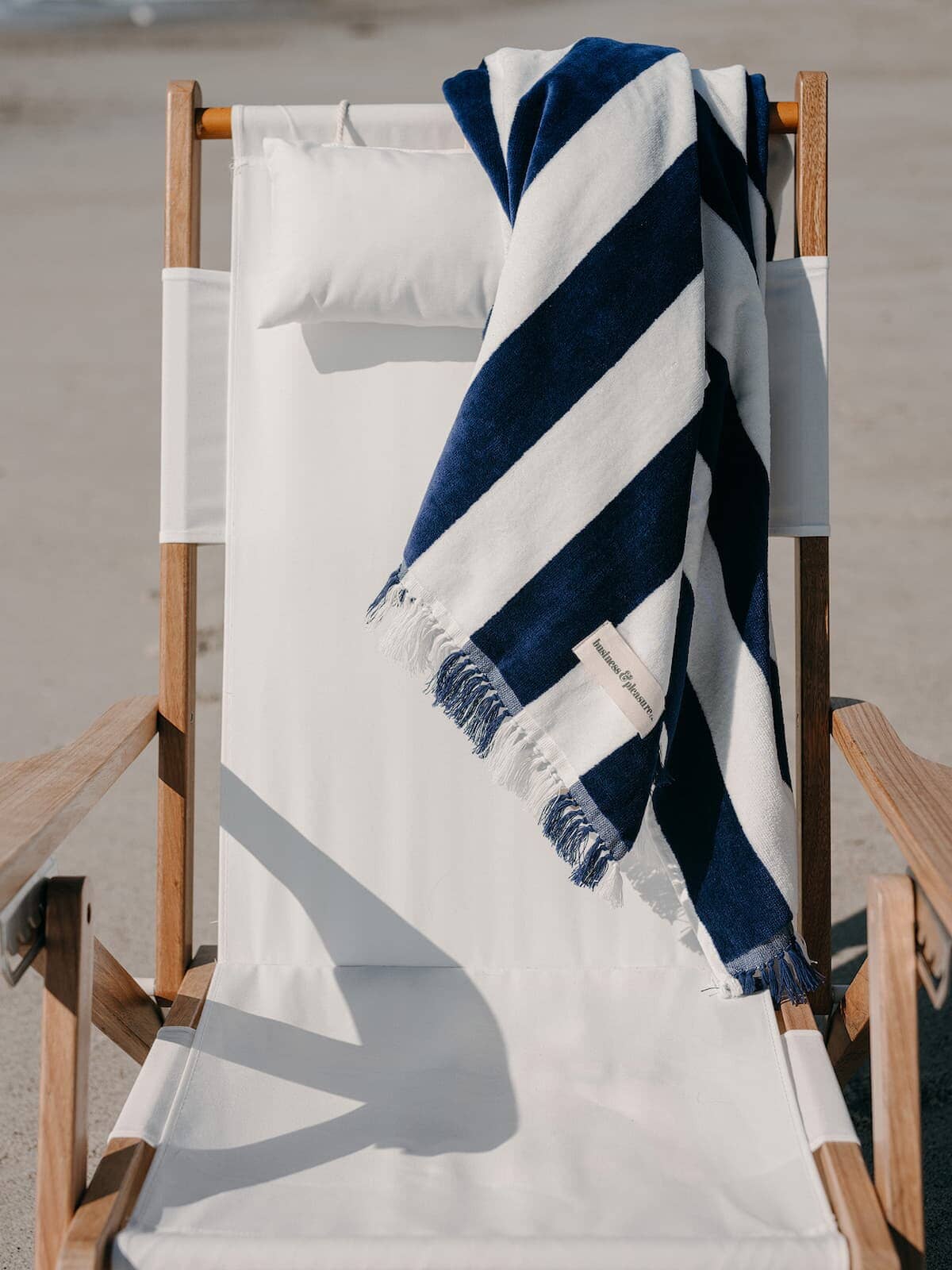 navy capri holiday beach towel draped over white tommy chair on the beach