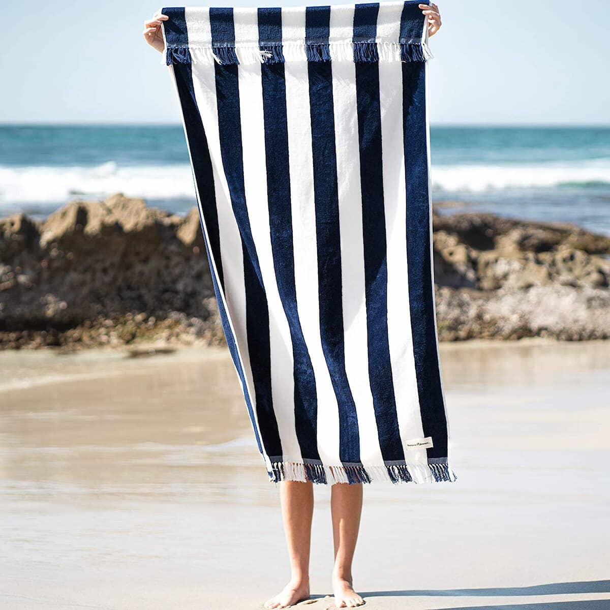 lady on a beach holding up the navy holiday beach towel