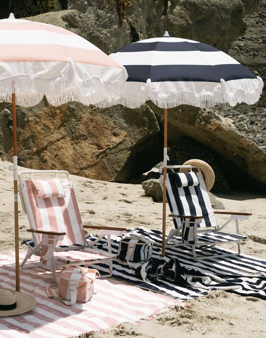 beach scene with pink and navy umbrellas, towels and coolers