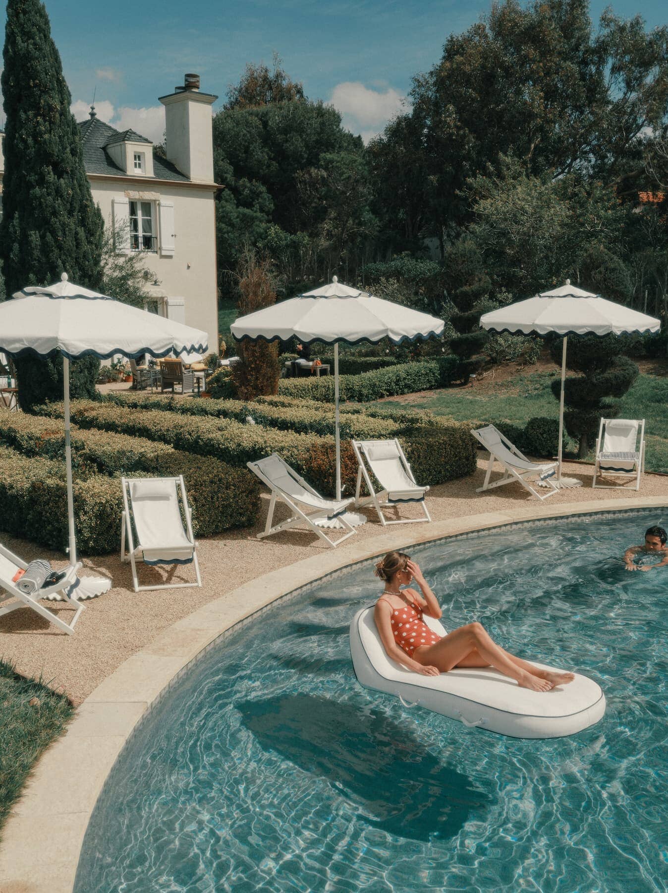 pool setting with riviera white sling chairs and market umbrellas