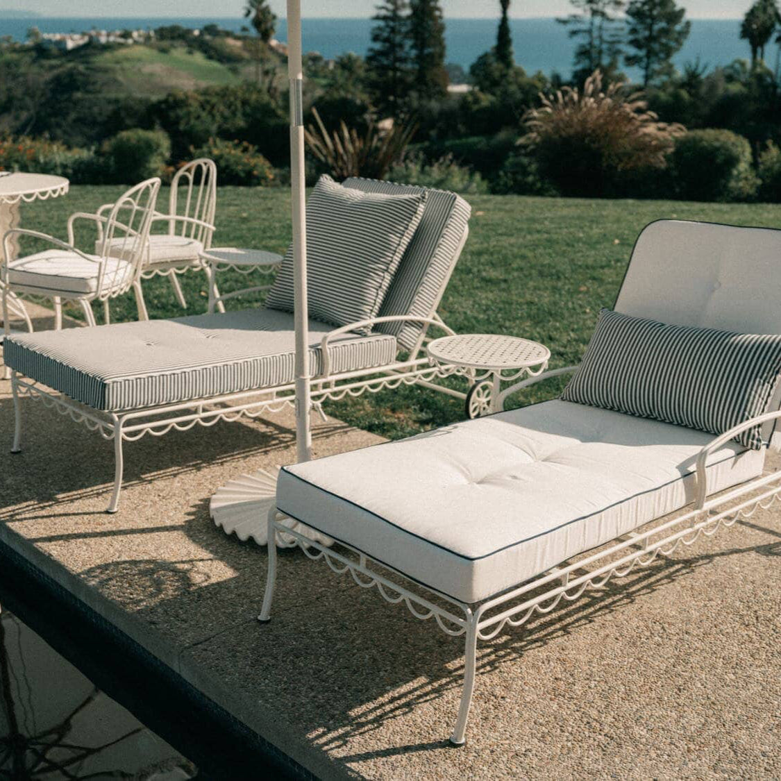 white sun loungers next to a pool with white and navy stripe cushions