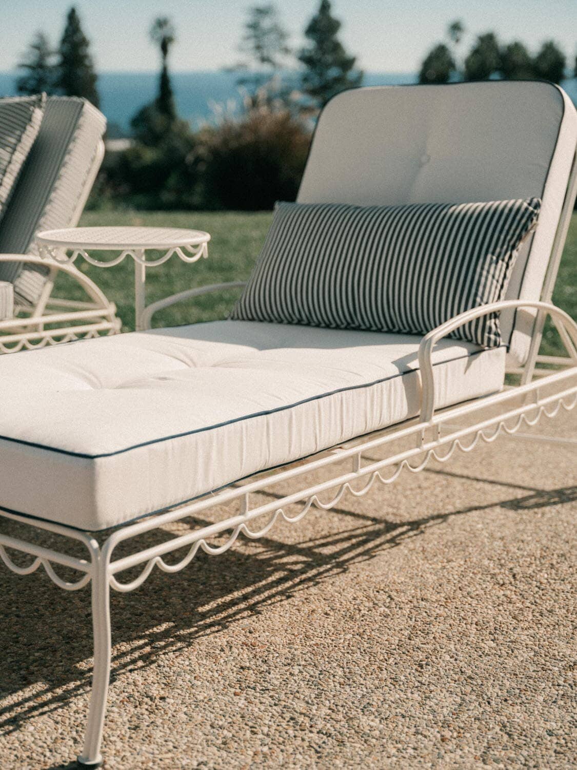 white sun loungers next to a pool with white and navy stripe cushions